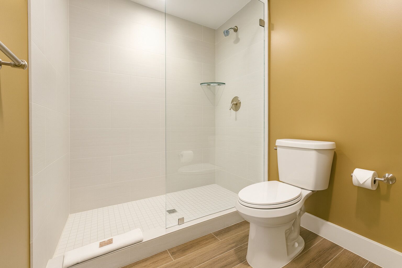 A bathroom with a shower, toilet, and a glass shower door.
