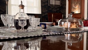 Een eettafel met een kristallen karaf, glazen en borden, met reflecties op het gepolijste oppervlak.