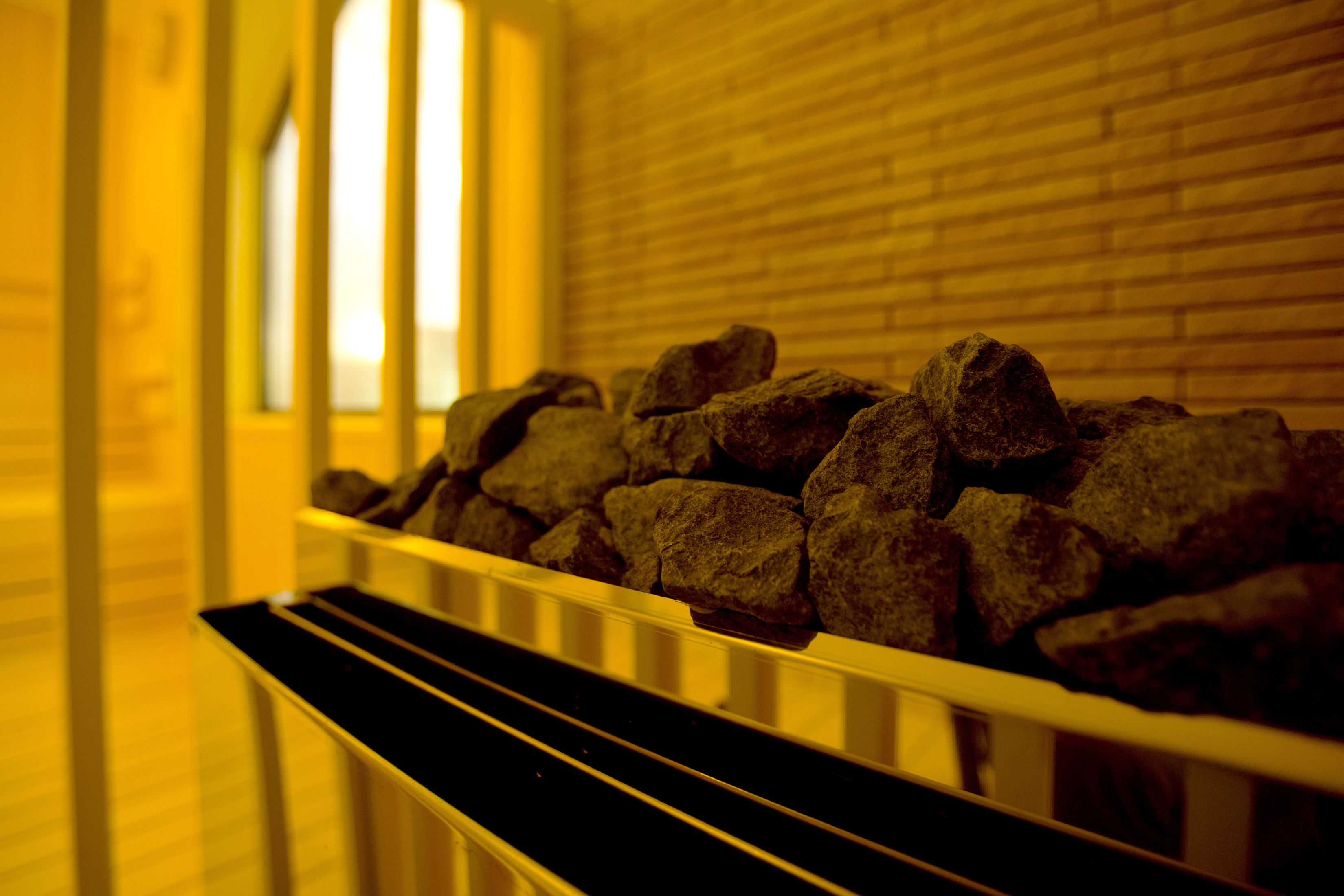 A row of dark stones in a white metal railing, with a brick wall and a window in the background.