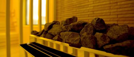 A row of dark stones in a white metal railing, with a brick wall and a window in the background.