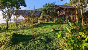 A tropical resort with thatched-roof cabins surrounded by lush greenery and a view of the sea. - Erlittop Nature Lodge (El Nido)