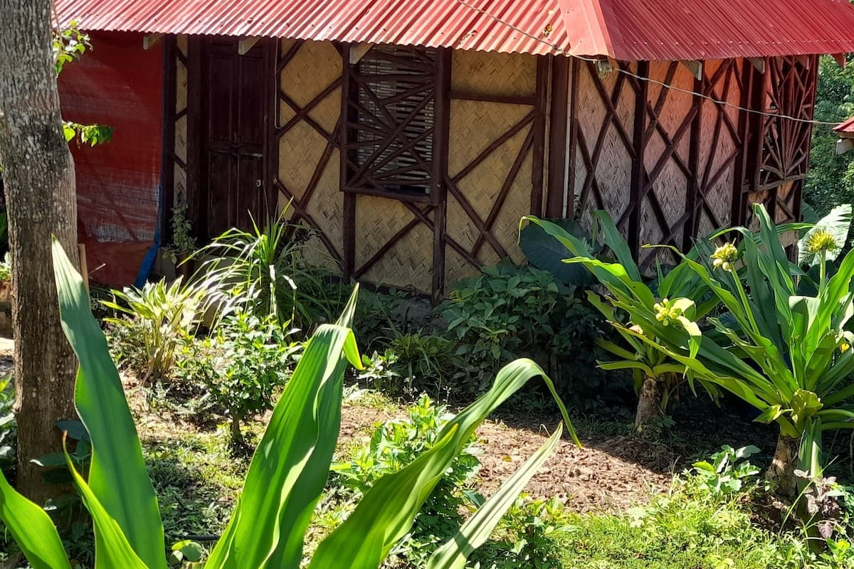 Une petite maison de plain-pied, avec un toit en tôle ondulée rouge et un motif décoratif en treillis de bois.