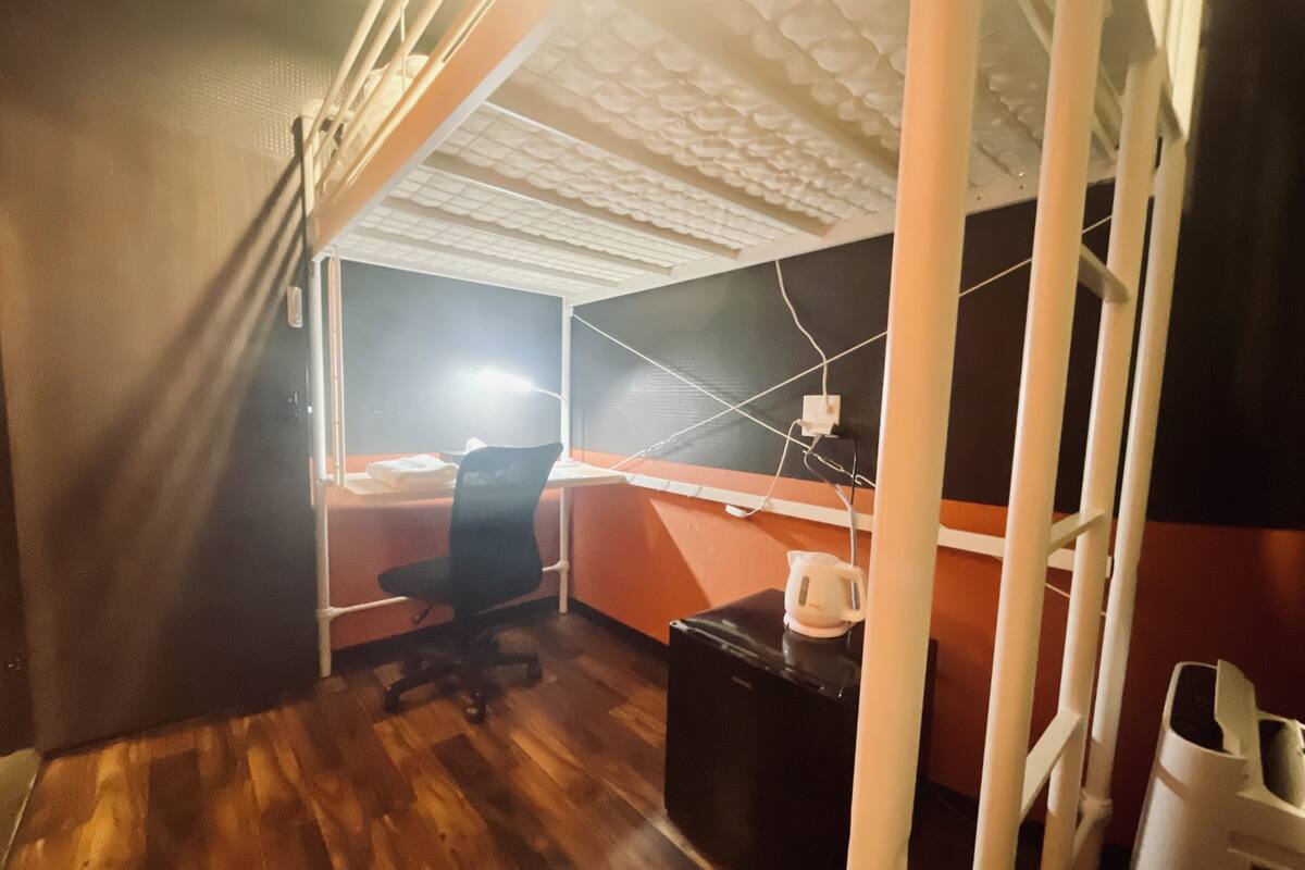 Ein kompakter Arbeitsbereich mit Schreibtisch, Stuhl und Kaffeemaschine.