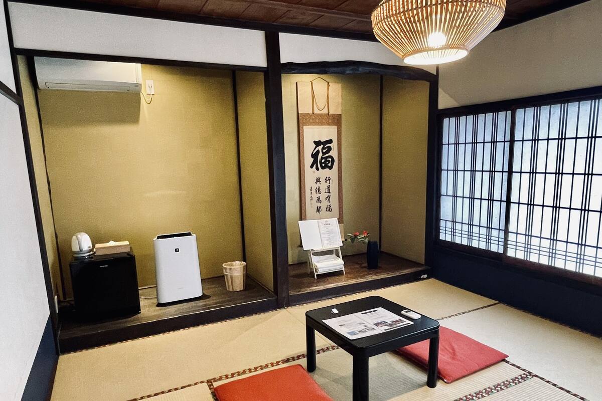Ein traditioneller japanischer Raum mit Tatami-Boden, einem niedrigen Tisch mit einer Speisekarte und einem Shoji-Bildschirm mit einer Kalligrafie-Aufschrift.