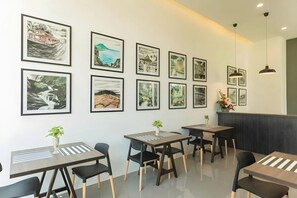 A modern dining area with tables, chairs, and framed artwork on the wall. - Pimdara Hotel (Chanthaburi)