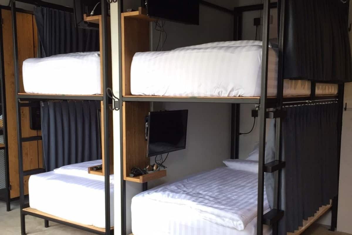 A bunk bed room with a television on the wall, wooden shelves, and a desk.