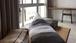 A modern room with large windows, a bench, a small table, and a chair. - Bedgasm Hostel Chanthaburi (Chanthaburi)