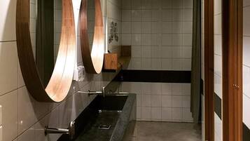 Un baño moderno con encimera negra, tres espejos grandes y dos lámparas colgantes.