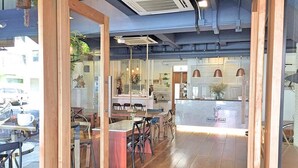 A restaurant interior with wooden flooring, glass partitions, and a reception desk. - Bedgasm Hostel Chanthaburi (Chanthaburi)