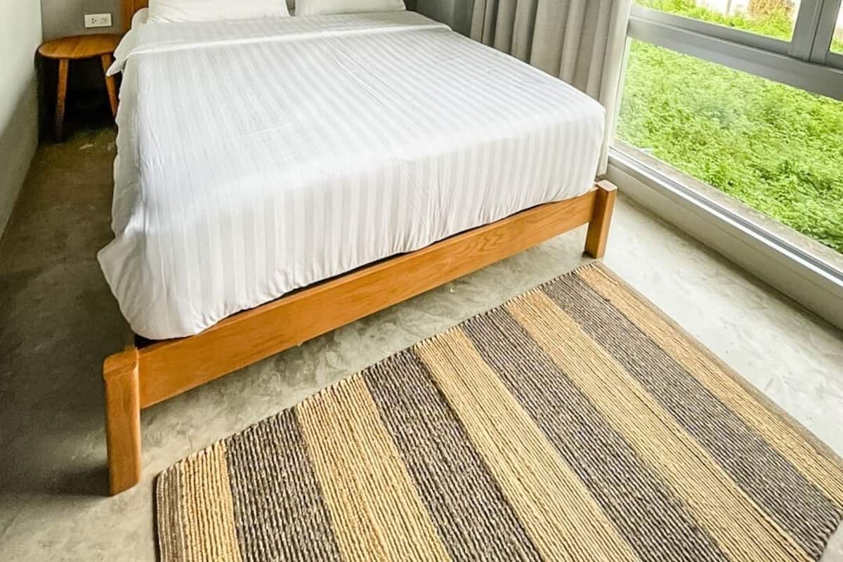 A bedroom with a large bed, two bedside tables, a window with curtains, and wall art.
