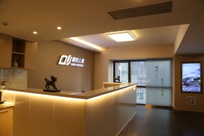 A reception area with a modern design, featuring a reception desk, a wall-mounted sign, and a large window with a view. - Cherry Residences May-Fourth Square (Qingdao)