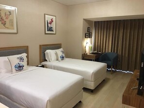 A hotel room with two beds, a desk, a chair, and a television. - Cherry Residences May-Fourth Square (Qingdao)