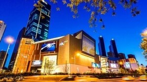 Um edifício moderno com uma placa de destaque, rodeado por outros edifícios altos.