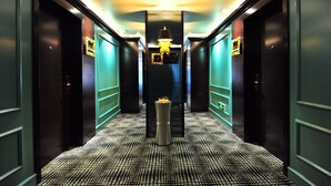 Un corridoio con pavimento decorato, una colonna centrale e un lampadario.