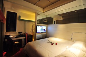 A hotel room with a bed, a desk with a computer, a television, and a mirror. - Boutique Hotel (Beijing)