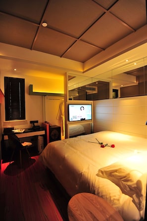 A hotel room with a bed, a desk with a computer, a television, and a mirror. - Boutique Hotel (Beijing)