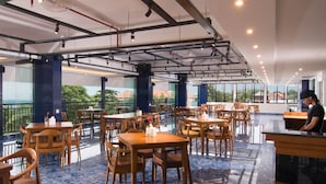 Un restaurante espacioso con techos altos, mesas y sillas de madera y amplios ventanales con vistas al exterior.