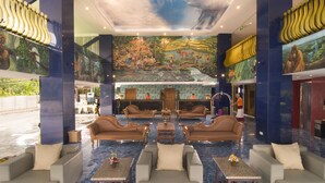 Un vestíbulo con zonas de estar, un mostrador de recepción y un mural en el techo.