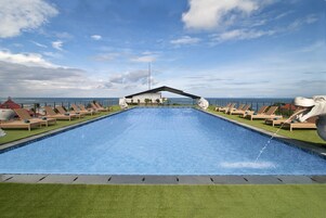 Una piscina al aire libre, sombrillas, sillones reclinables de piscina