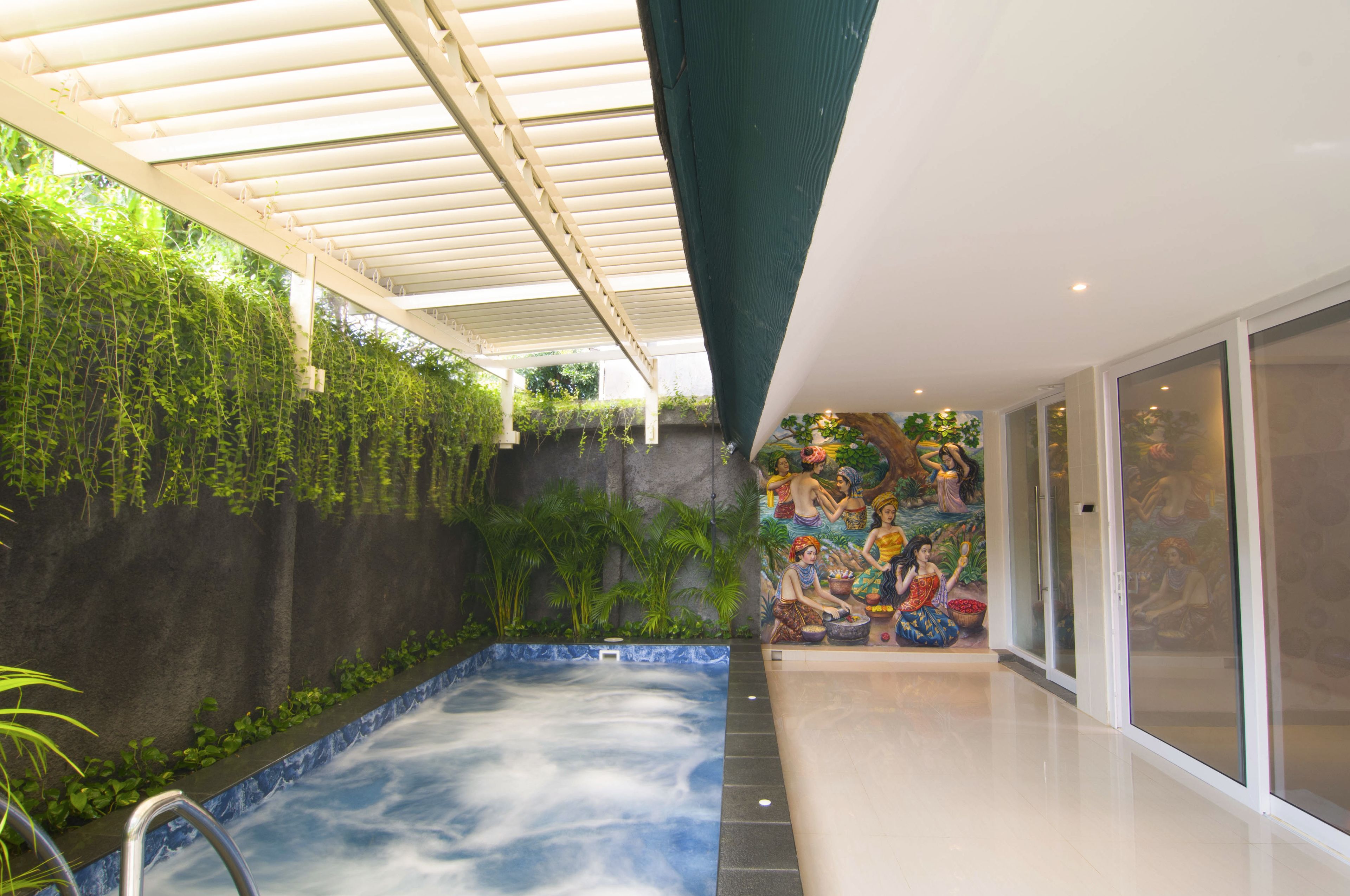 A spa area with a hot tub, green walls, and a mural.