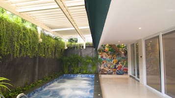 A spa area with a hot tub, green walls, and a mural.