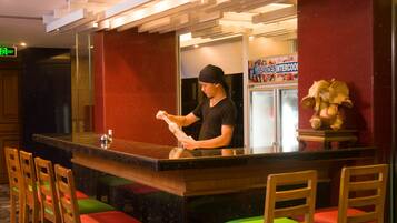 A bar area with a counter, chairs, and a person behind the counter.