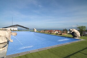 Una piscina al aire libre, sombrillas, sillones reclinables de piscina