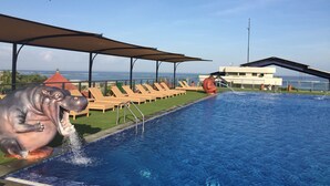 Una piscina con fuente, sillas de descanso y vista al océano.