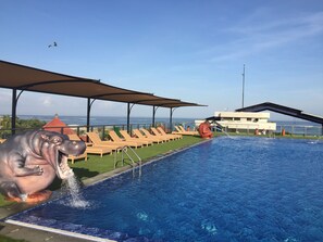 Een buitenzwembad, parasols bij het zwembad en ligstoelen