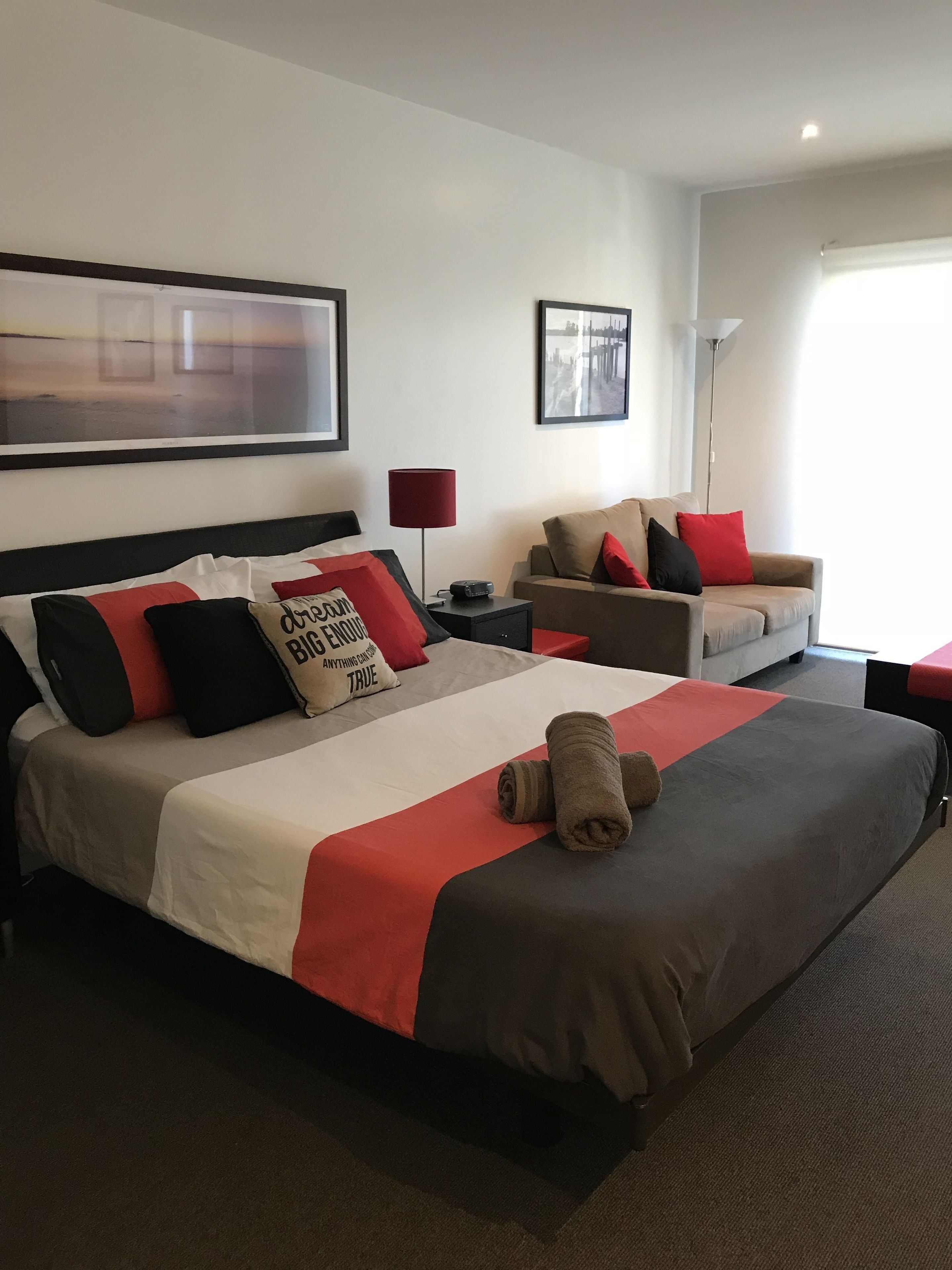 Ein Hotelzimmer mit einem großen Bett, einer Sitzecke, einem Schreibtisch und einer Lampe.