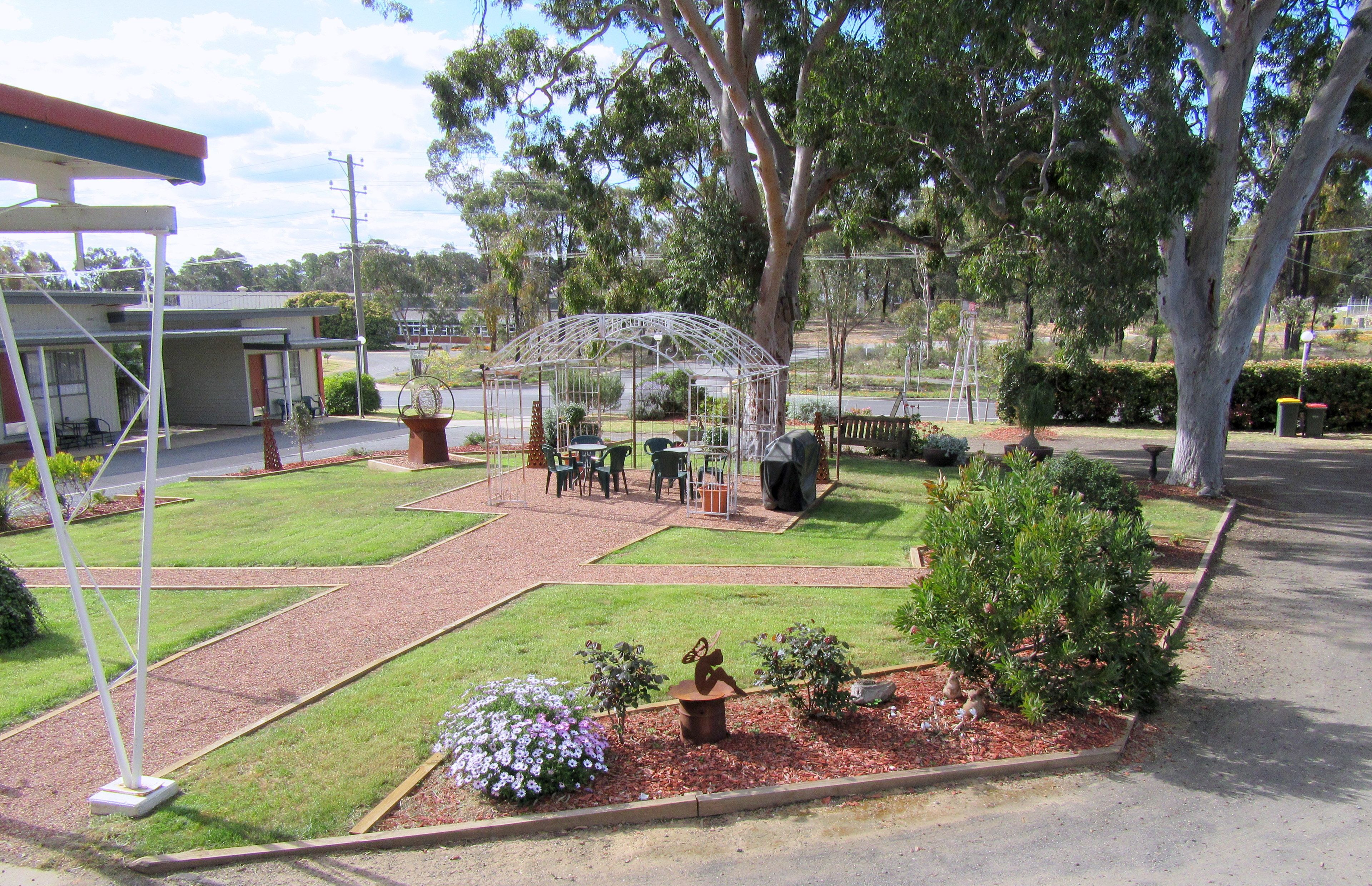 Un'area giardino con un gazebo, posti a sedere e una piccola statua.
