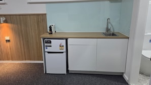 A compact kitchen with a built-in dishwasher, a sink, and a wooden countertop. - The Highlander Motel - 24HR Check In (Maryborough)