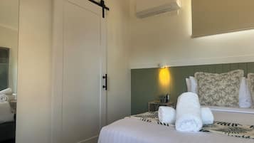 A hotel room with a bed, a sliding door, an air conditioning unit, a bedside lamp, and a headboard with a floral pattern.