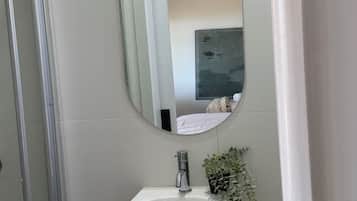 A bathroom with a white sink, a mirror, and a shower.