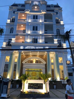 A multi-story hotel with a grand entrance, featuring a welcoming sign and a decorative archway. - Nice Life Hotel Phu Quoc (Phu Quoc)