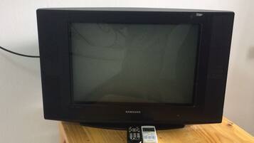 A Samsung television on a wooden stand with a remote control beside it.