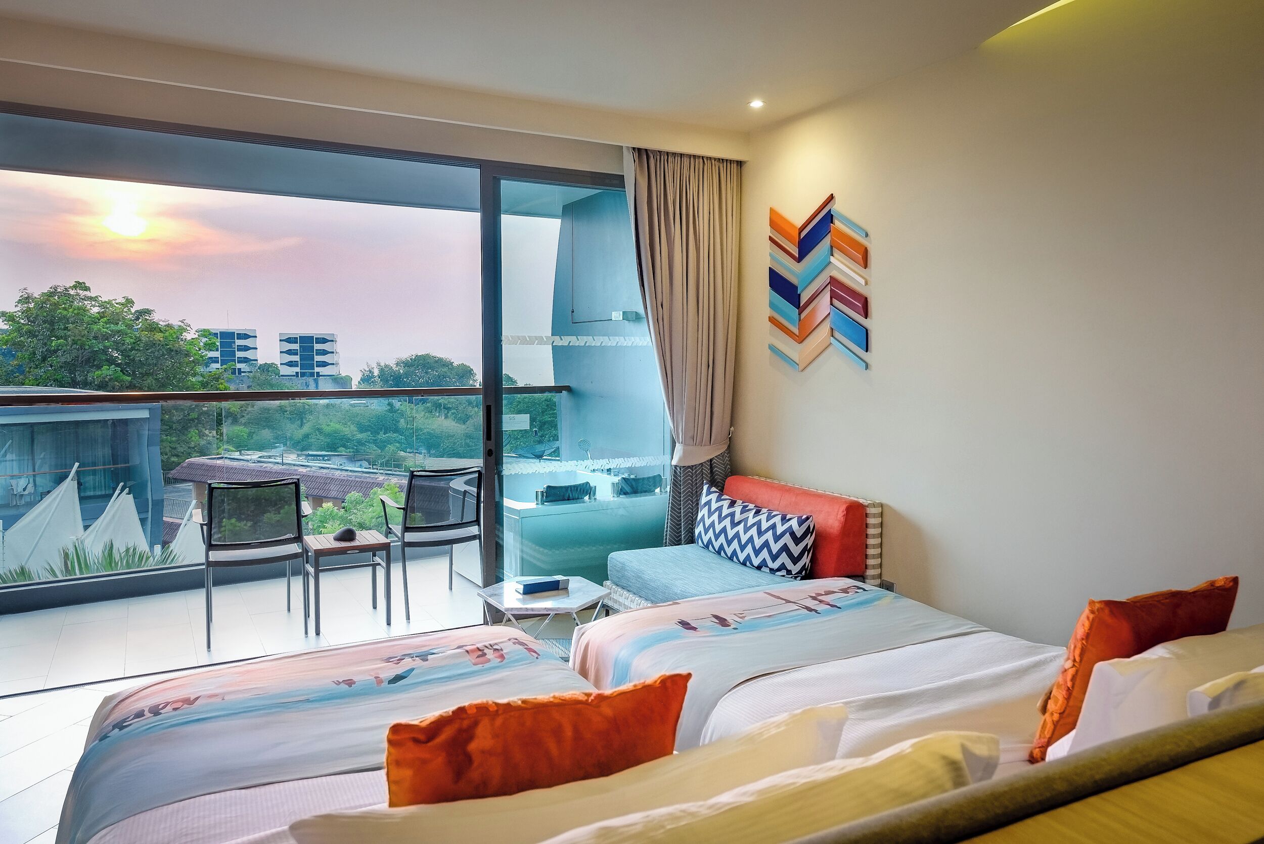 Une chambre d’hôtel moderne dotée d’un balcon, de grandes fenêtres et offrant une vue sur le paysage urbain.