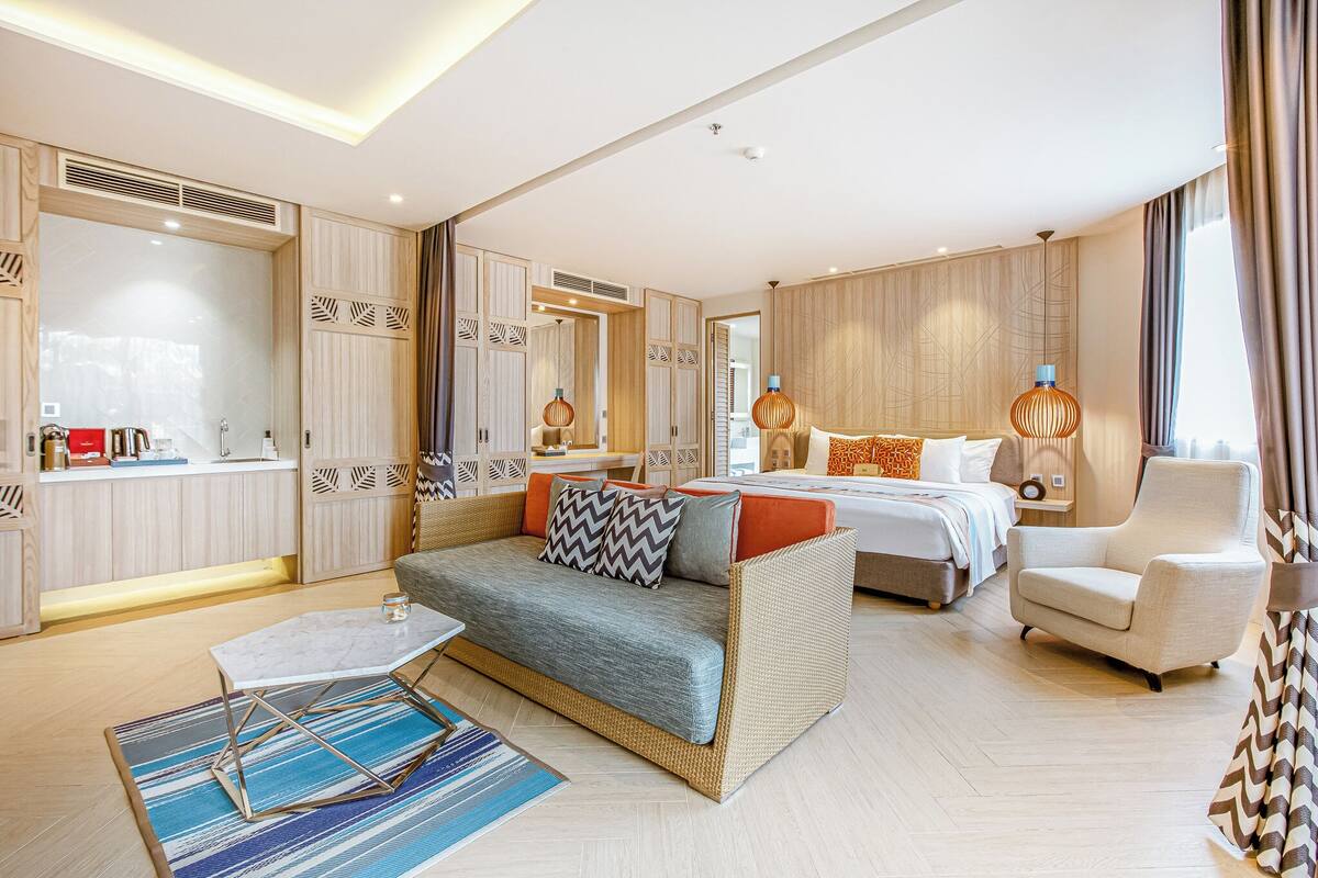 Una habitación de hotel moderna con un sofá, una cama, una silla y una mesita.