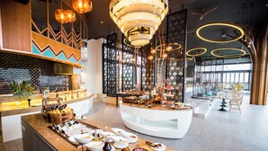 Eine moderne Hotellobby mit einer zentralen Anrichtetheke, umgeben von Sitzbereichen und dekorativer Beleuchtung.