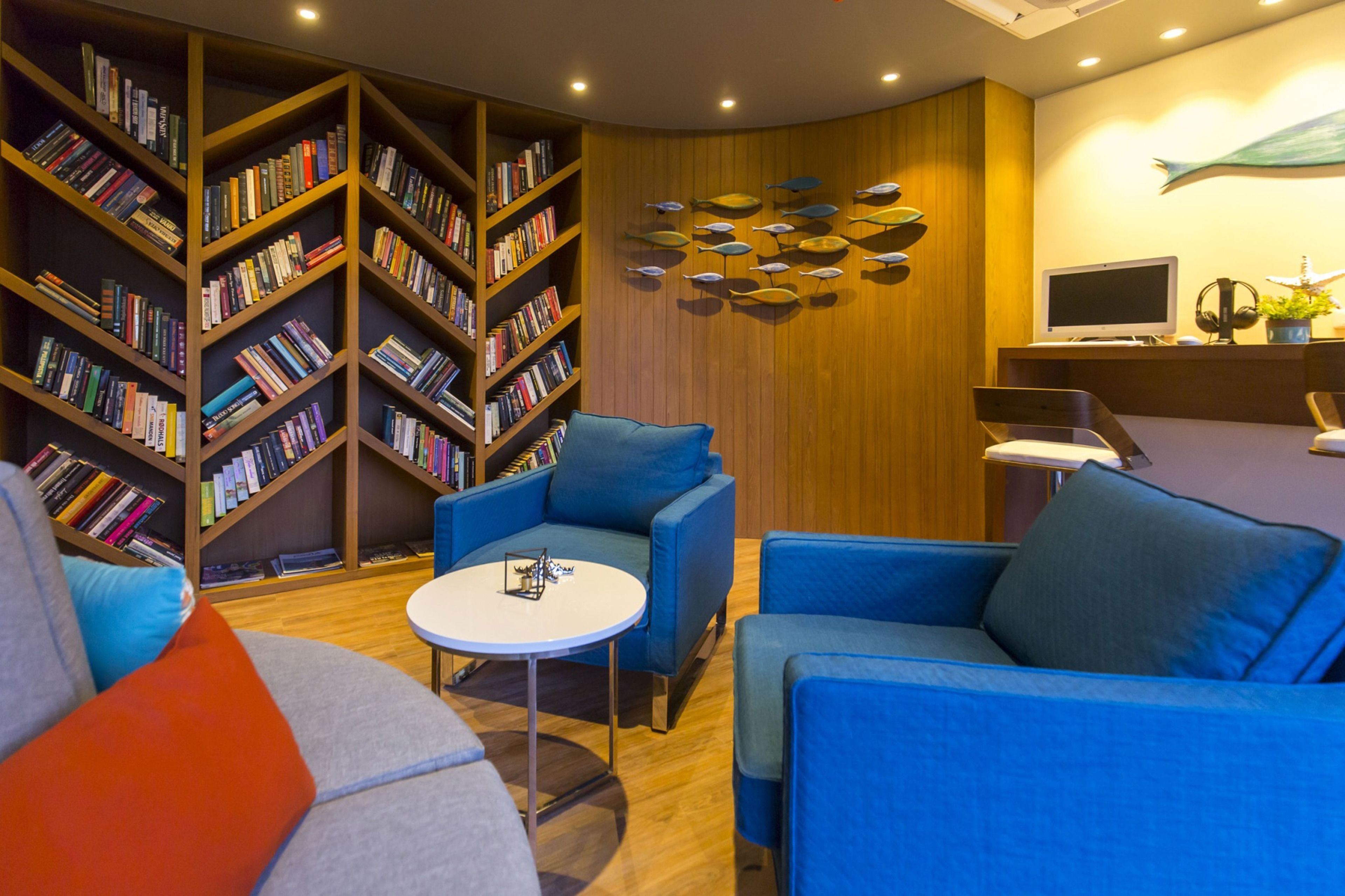 A modern library with blue sofas, a white table, and bookshelves filled with books.