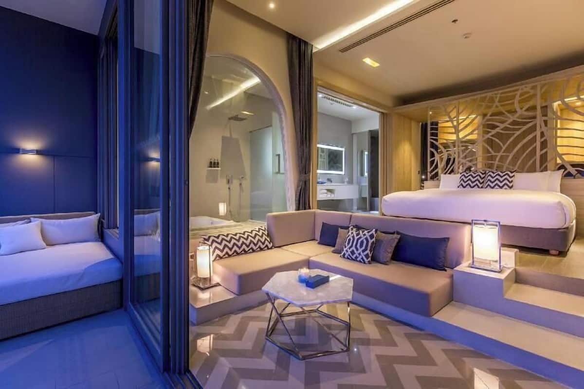 Una habitación de hotel moderna con cama, sofá y una mesita de café.