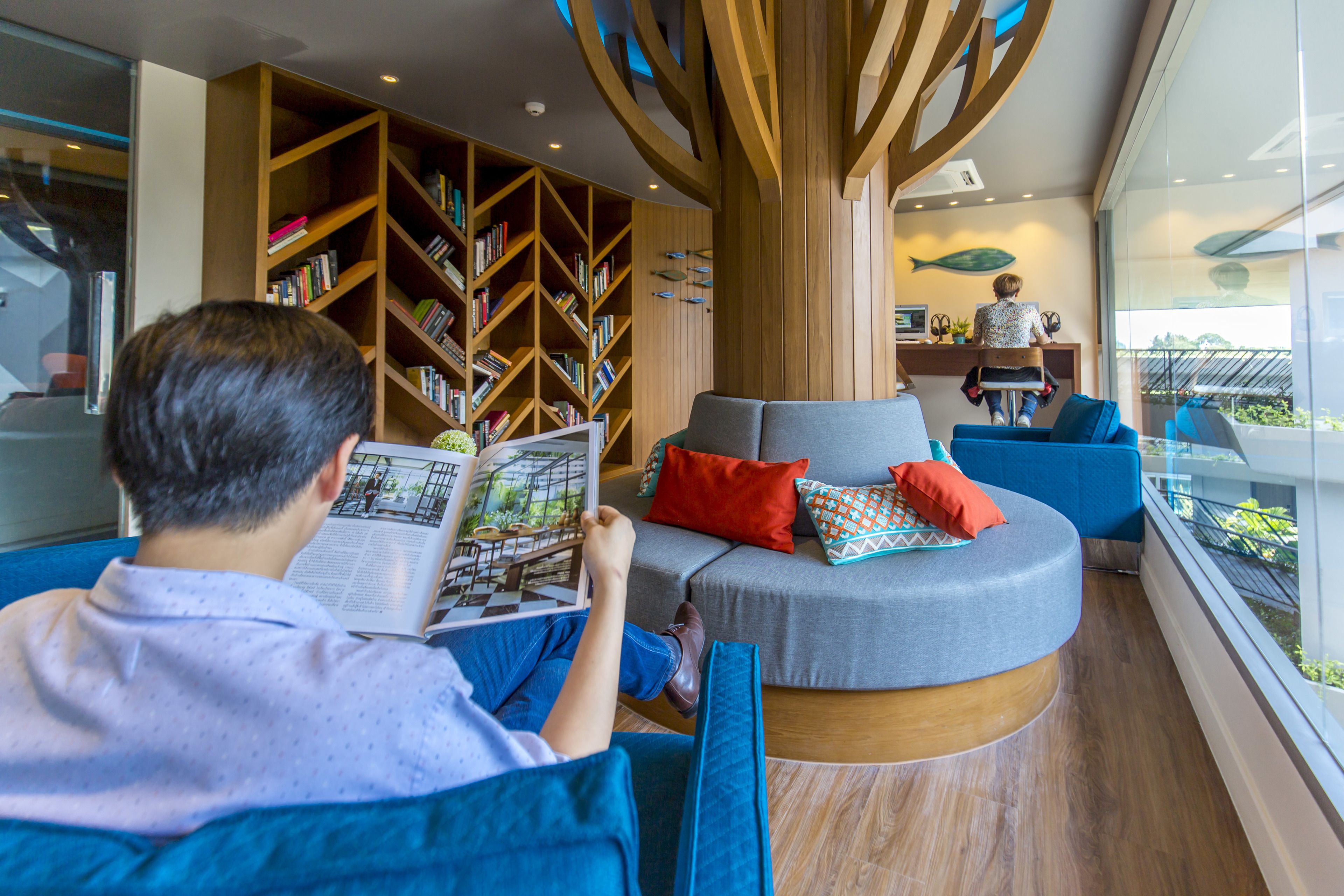 Un interior moderno con una zona de estar circular, una estantería de madera y un escritorio con una computadora.