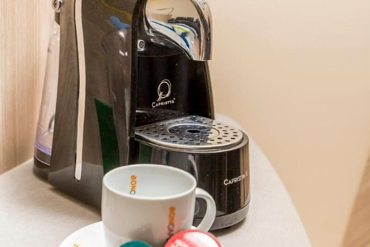 A coffee machine, a cup, and two capsules on a table.