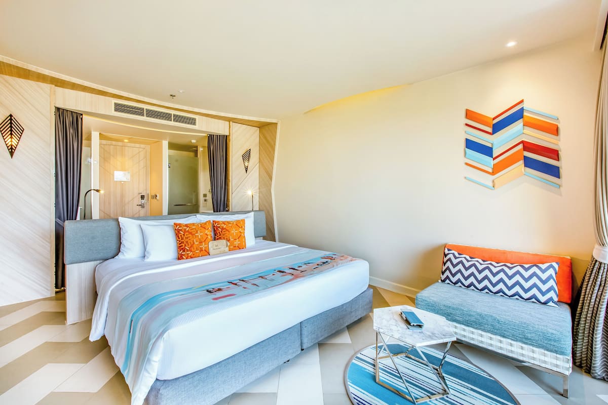 Una habitación de hotel moderna con una cama grande, un sofá y una mesita.