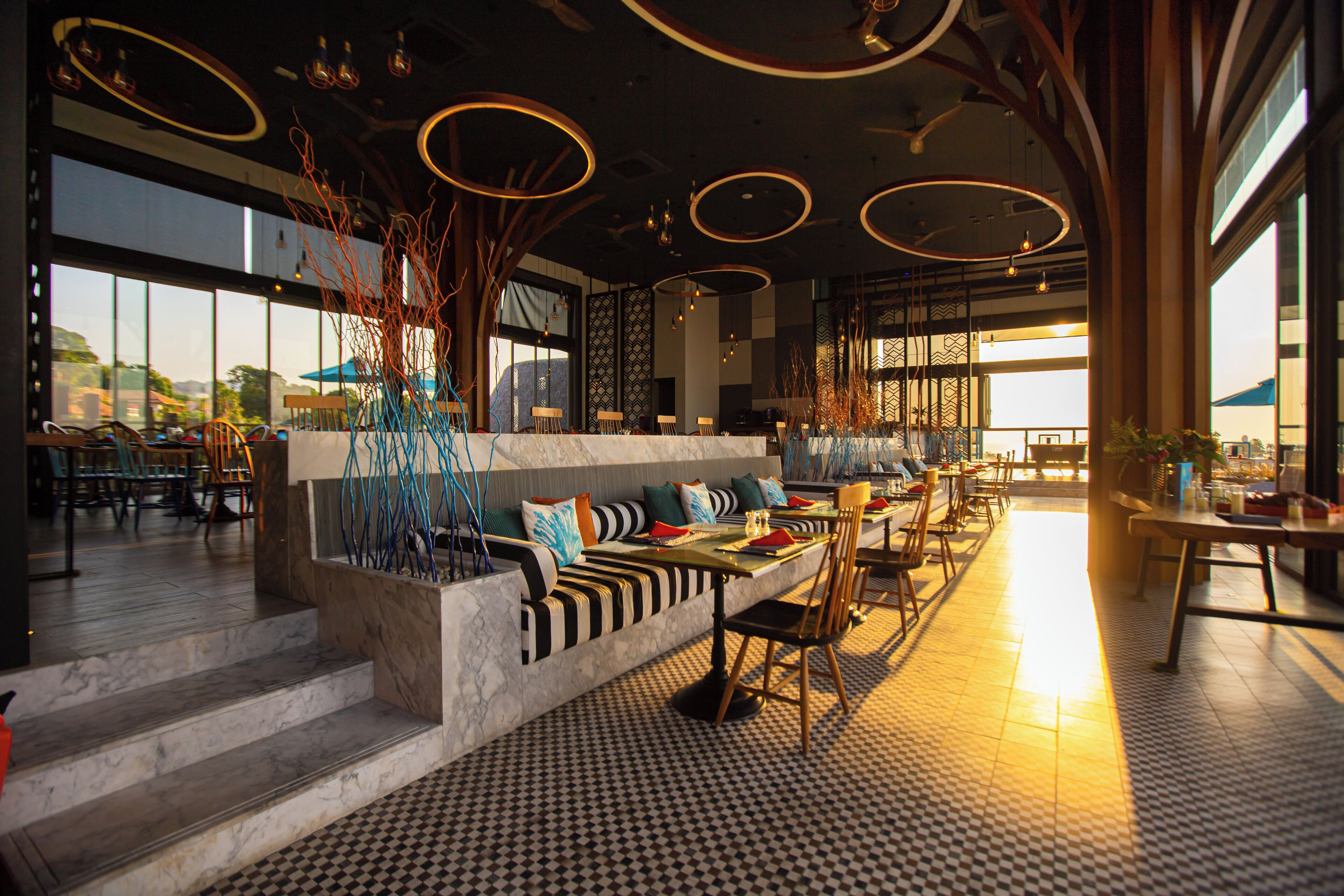 Un restaurante moderno con una barra larga, zona de estar con bancos y vistas a la ciudad.