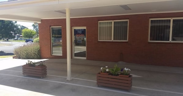 A reception area with a brick facade, a glass door, and potted plants.