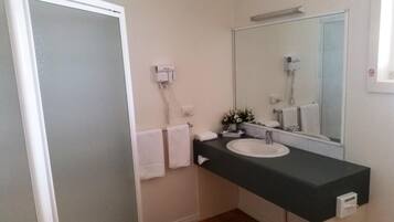 A bathroom with a white sink, a mirror, a towel rack, and a hairdryer.