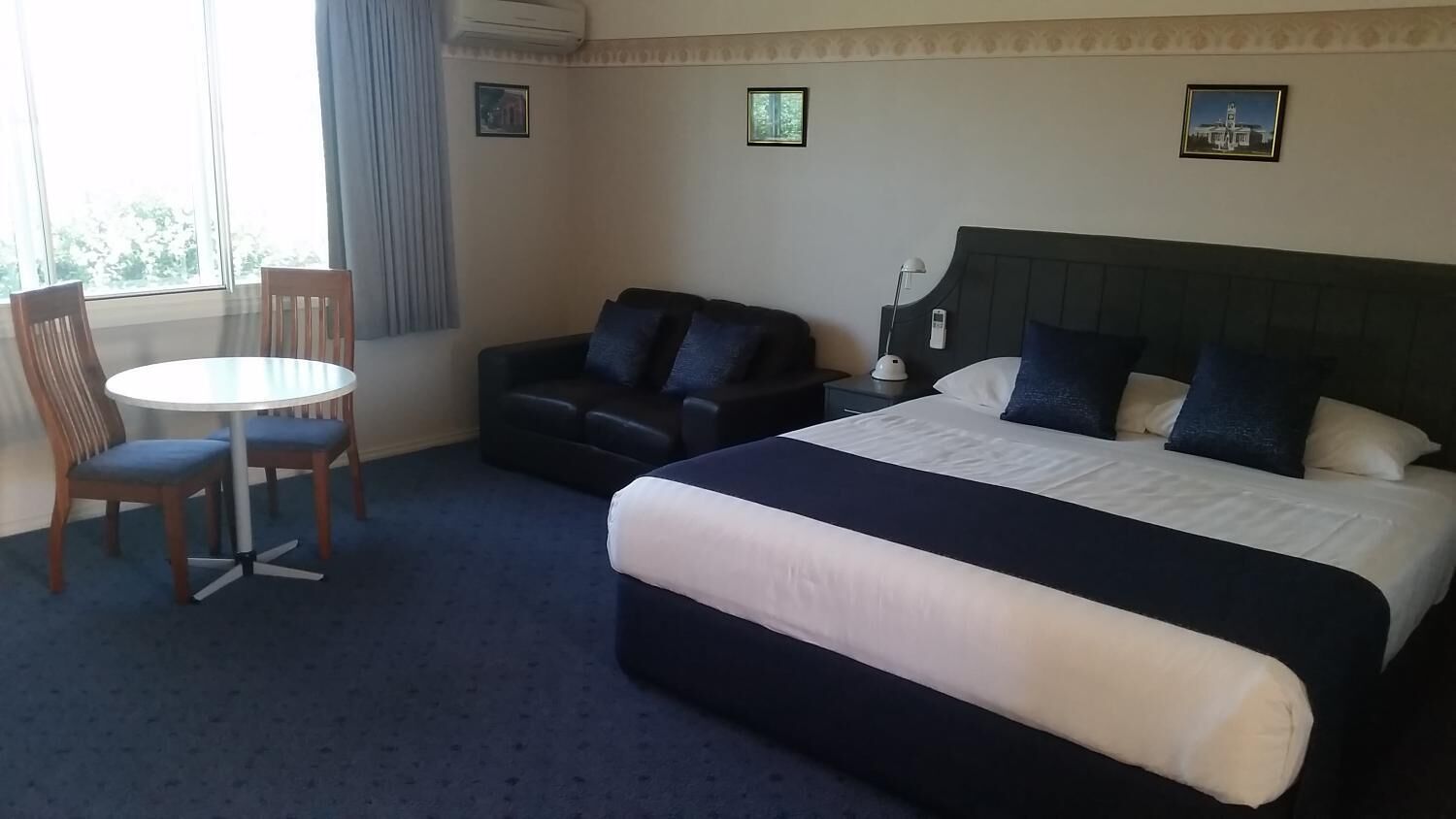 A hotel room with a bed, a sofa, a dining table, and chairs.