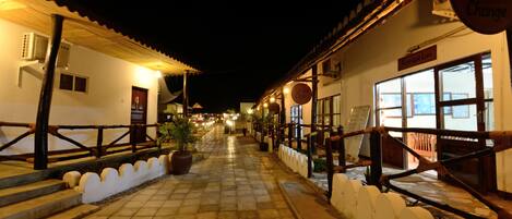 Vista nocturna de una calle bordeada de edificios, incluyendo una zona de recepción y un letrero que dice 'Bureau du Change'.