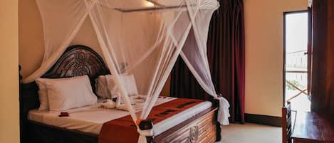 A four-poster bed with a canopy, a wooden headboard, and a red bedspread.
